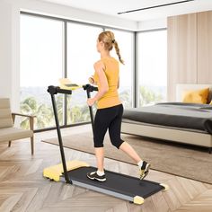 a woman is running on a treadmill in a bedroom with a view out the window