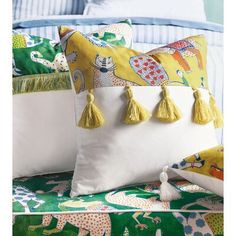 two pillows with tassels on them sitting next to each other in front of a bed