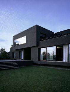 an exterior view of a modern house with grass and steps leading to the front door