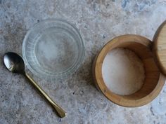 an empty glass cup next to a wooden lid and spoon on a marble counter top