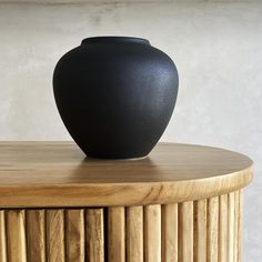 a black vase sitting on top of a wooden table