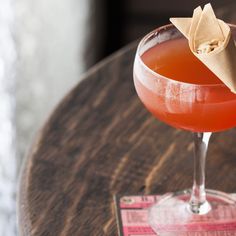 a drink sitting on top of a wooden table next to a paper origami