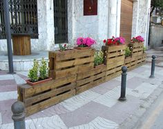 wooden planters are lined up on the side of a building with flowers in them