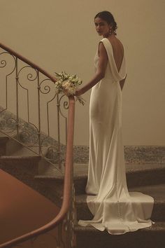 a woman in a white dress standing on some stairs