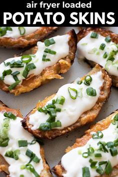 baked potato skins with sour cream and scallions on top, sitting on a baking sheet