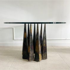 a glass table topped with metal sculptures on top of a tiled floor next to a white wall