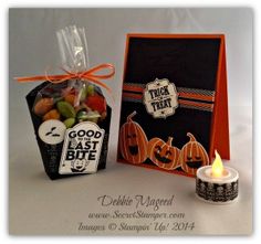 an orange and black halloween treat bag next to a candle