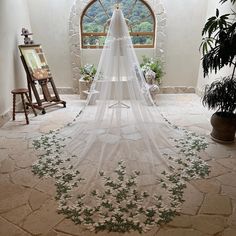 a wedding veil hanging from the ceiling in a room with stone flooring and potted plants