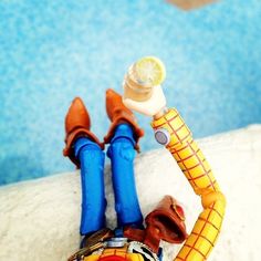 a toy figure laying on top of a white surface next to a swimming pool with a lemon slice in it's mouth