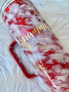 a red and white tumbler with the word grandma written in gold glitter on it