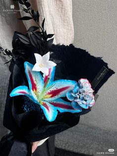 a woman holding a black hat with flowers on it