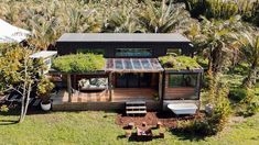 an aerial view of a small house in the middle of palm trees and lawn furniture