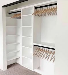 an empty white closet with wooden clothes hangers