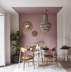 a dining room with pink walls and chandelier hanging from the ceiling over a table