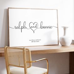 a white vase sitting on top of a wooden table next to a framed sign that says, ralph and bonnie