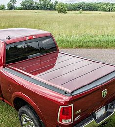 a red pick up truck parked on the side of a road in front of a field