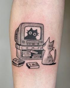 a black and white tattoo with a cat watching tv