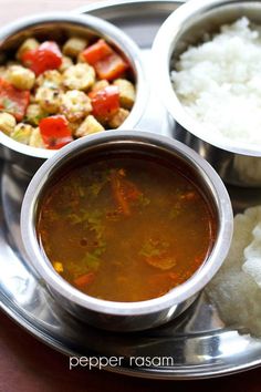 there are three bowls of food on the silver plate and one bowl has rice in it