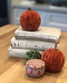 two pumpkins are sitting on top of three books, one is red and the other is white