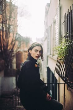 a woman is sitting on the steps in front of a building and looking off into the distance