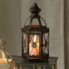 an old fashioned lantern with a lit candle in it on top of a stack of books