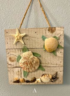 a wooden sign with seashells and starfish hanging from it's side