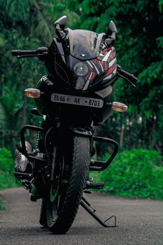 the motorcycle is parked on the side of the road near some bushes and trees in the background