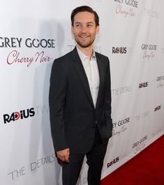 a man in a suit standing on a red carpet at the grey goose cherry noir event