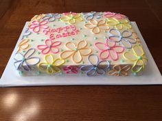 a birthday cake decorated with colorful icing on a white plate and wooden table top