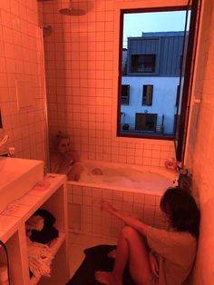 two people sitting in a bathtub with orange light coming through the window and on the floor