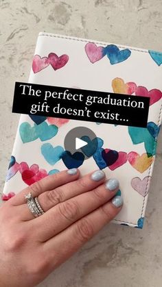 a woman's hand holding a book with hearts on it and the words, the perfect graduation gift doesn't exist