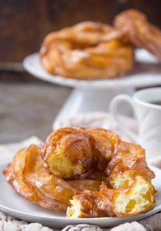 two white plates topped with donuts next to a cup of coffee and saucer