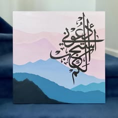 an arabic calligraphy is displayed on a blue couch in front of some mountains and hills