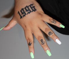 a woman's hand with green and white nail polishes on it, including the word hope