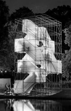 a large structure with scaffolding on it in the middle of a lake at night