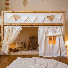 a teddy bear sitting on top of a bunk bed in a room with white curtains