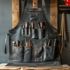 an apron is hanging on the wall with pens and pencils in it's pockets