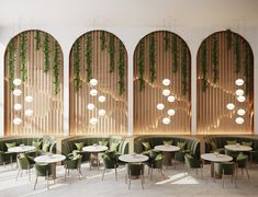 an empty restaurant with round tables and green velvet booths, hanging plants on the wall