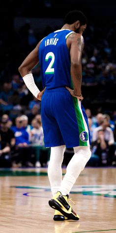 a man standing on top of a basketball court wearing a blue uniform and white pants