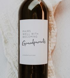 a bottle of wine sitting on top of a white blanket next to a bag with the words paris will be becoming grandparents written on it