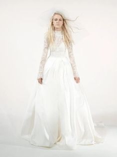 a woman in a white wedding dress with long hair and veil on her head is posing for the camera