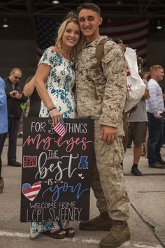 a man and woman standing next to each other holding a sign