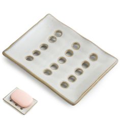 a white and grey plate with some pink buttons on it next to a square object