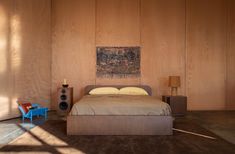 a bedroom with wood paneling and a bed in the middle, next to a blue chair