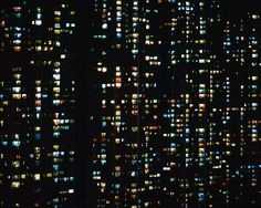 an aerial view of the city at night with lots of windows lit up in different colors