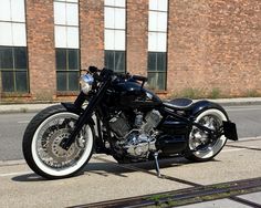 a black motorcycle parked next to a brick building