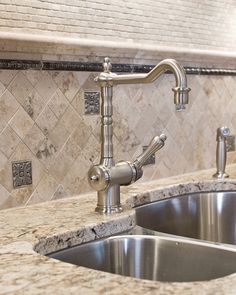 a kitchen sink with a faucet in the middle and marble counter tops above it