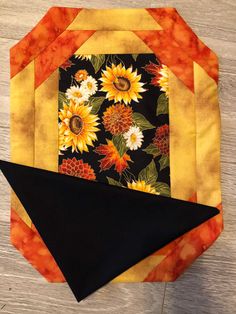 an orange and black piece of fabric with sunflowers on it sitting on a table