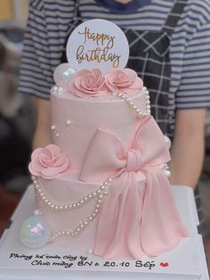 a birthday cake with pink roses and pearls on top is being held by a person