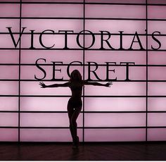 a woman standing in front of a wall with the words victoria's secret on it